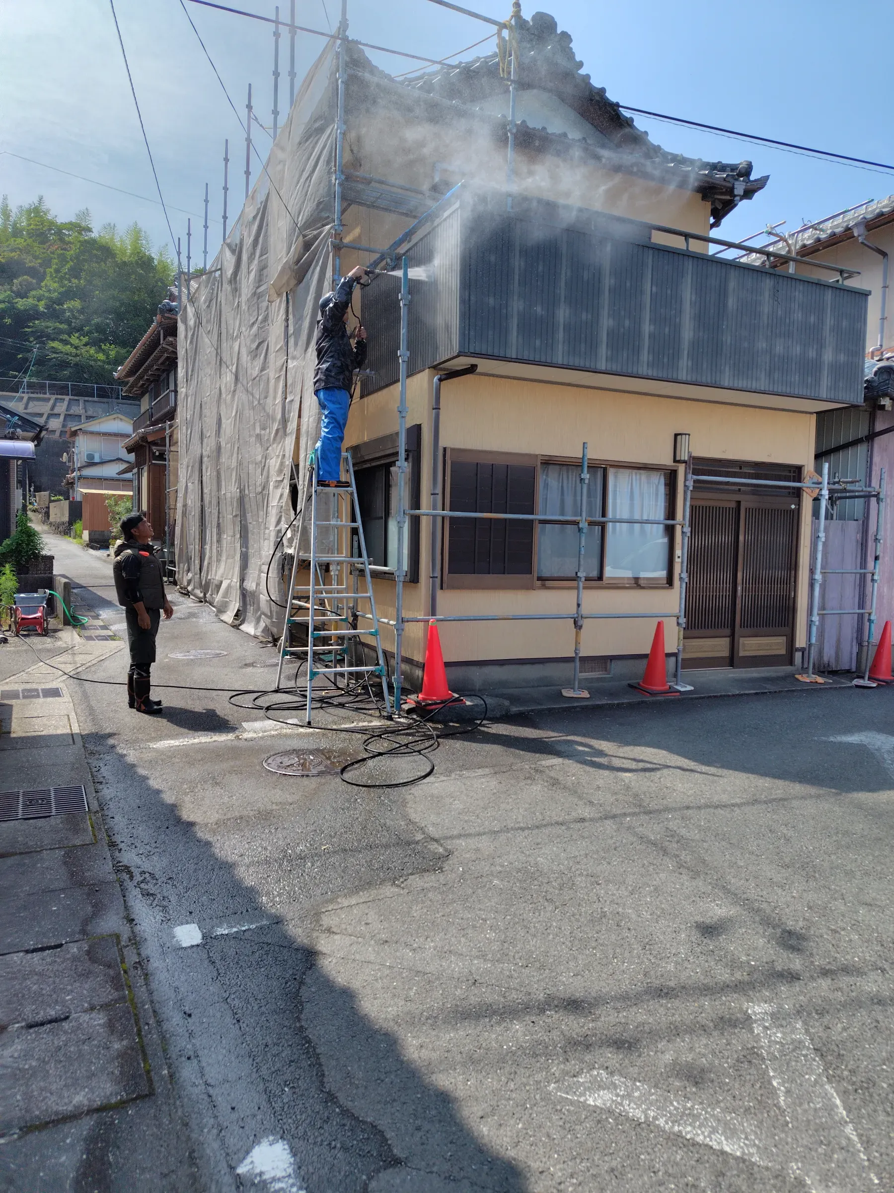 戸建住宅の外壁を高圧洗浄している施工中の様子