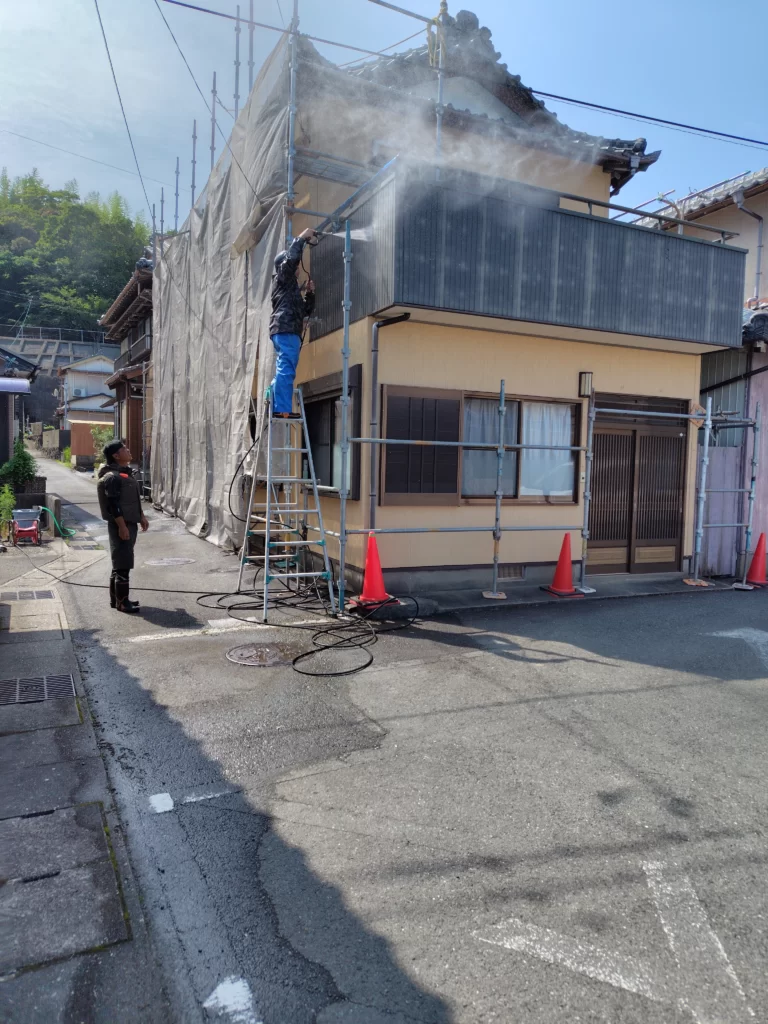 戸建住宅の外壁を高圧洗浄している施工中の様子